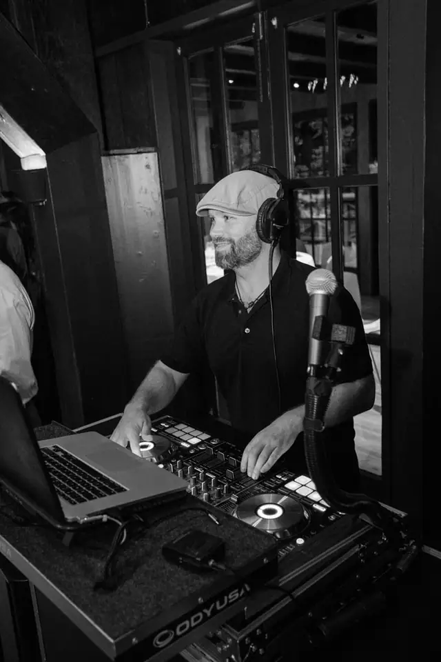 Black and white portrait of DJ Wayne Noel smiling at his controller at the Mill Valley Outdoor Art Club
