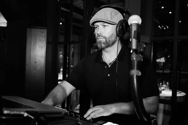 Black and white photo of DJ Wayne Noel focused on his controller during an event at the Mill Valley Outdoor Art Club