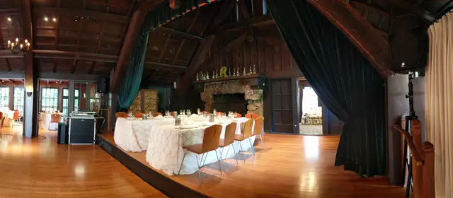 Panorama of the Mill Valley Outdoor Art Club great room with stone fireplace, head table on the stage and DJ booth set up on the floor