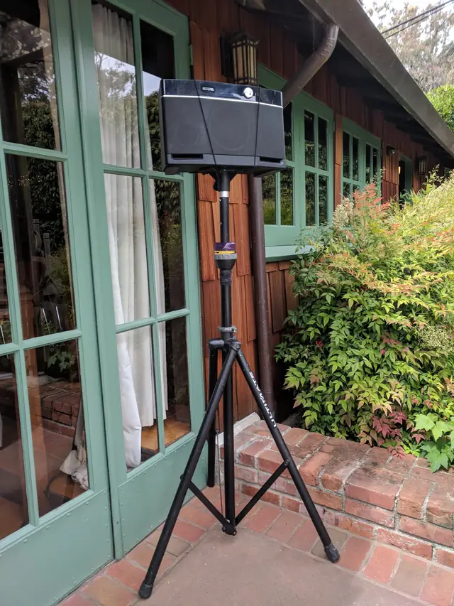Speaker on a stand beside green French doors on the brick terrace at the Mill Valley Outdoor Art Club