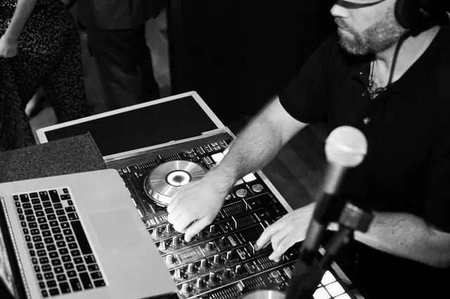 Black and white close-up of DJ Wayne Noel's hands on a controller during an event at the Mill Valley Outdoor Art Club