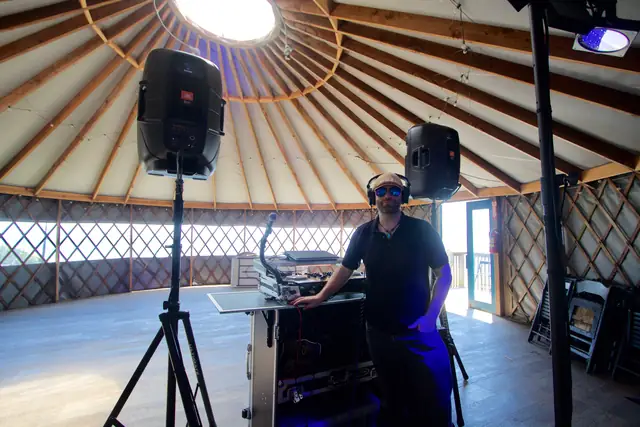 DJ Wayne Noel at his booth under the wooden rafters and skylight of the yurt at Slide Ranch