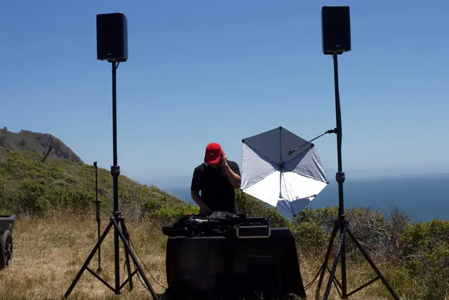 DJ at his table with speakers on stands on the hillside above the ocean at Slide Ranch