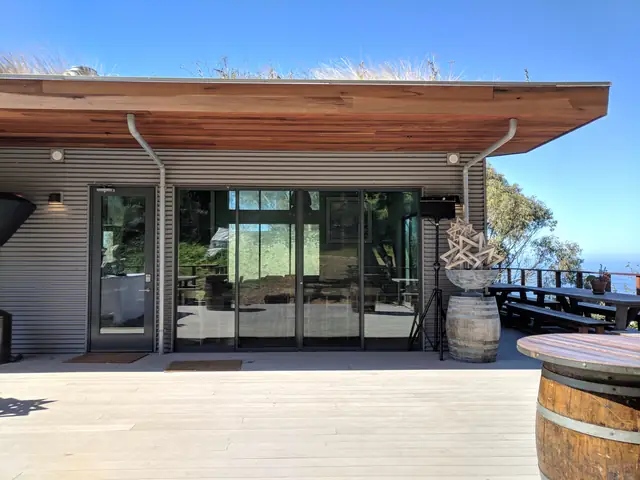 Deck and glass doors of the main building at Slide Ranch with a speaker on a stand beside a wine barrel