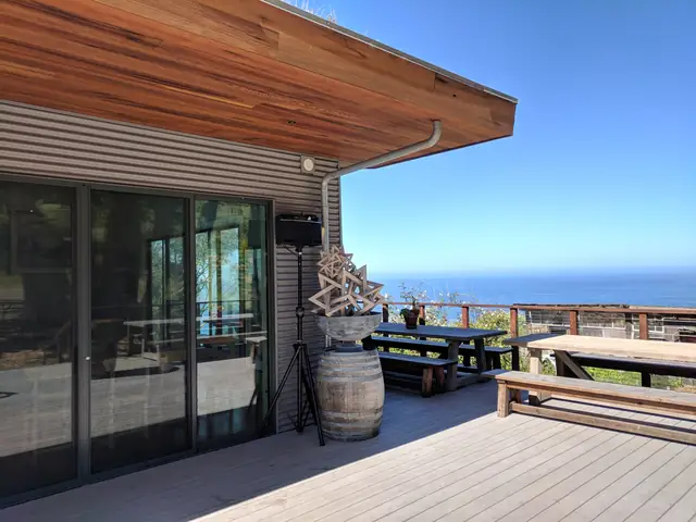 Ocean view from the deck at Slide Ranch with a DJ speaker beside a wine barrel and picnic tables