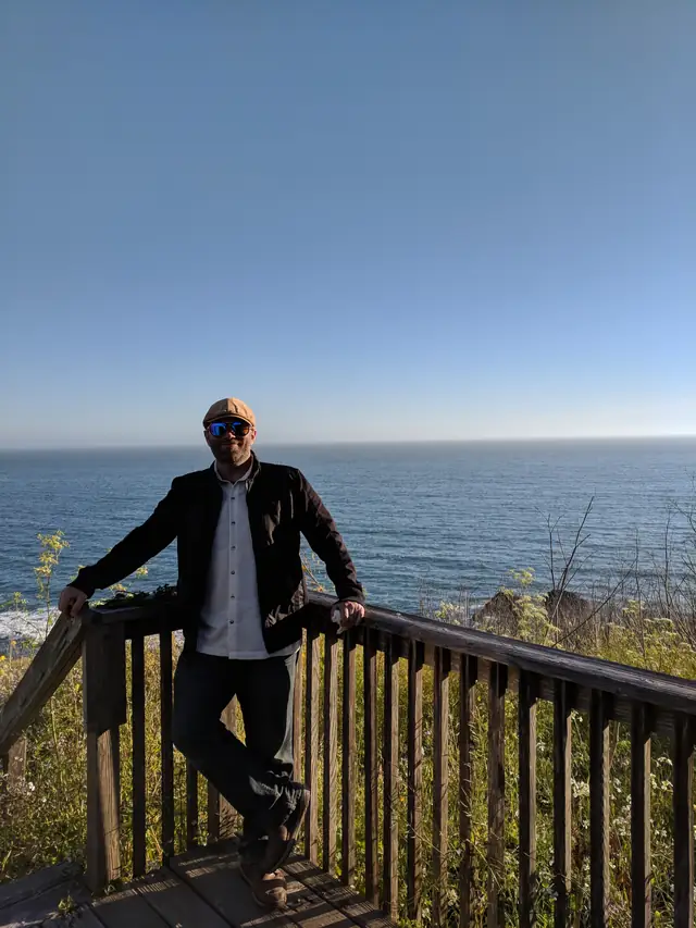 DJ Wayne Noel at the deck railing overlooking the ocean at Slide Ranch