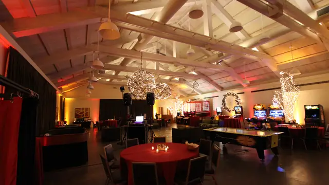 Long view of the Solage event hall with uplighting, candlelit tables and DJ Wayne Noel's booth