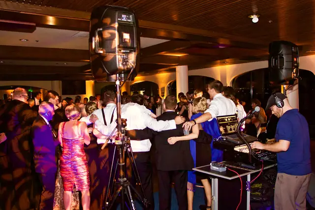 DJ Wayne Noel mixing at his table while guests dance in the gold-lit ballroom at St. Francis Yacht Club