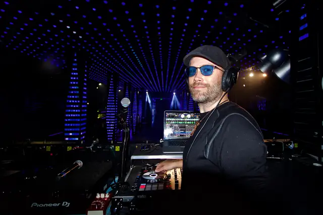 DJ Wayne Noel at the Pioneer DJ controller in the booth at Temple nightclub in San Francisco, with the blue LED ceiling and lit columns behind him