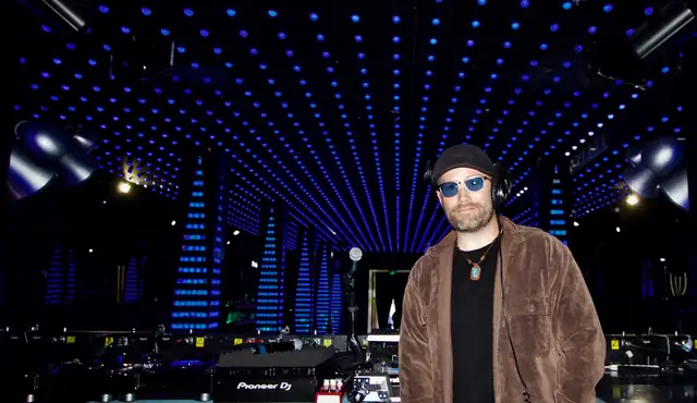 DJ Wayne Noel standing in the booth at Temple nightclub in San Francisco, with the blue LED ceiling and columns stretching behind him