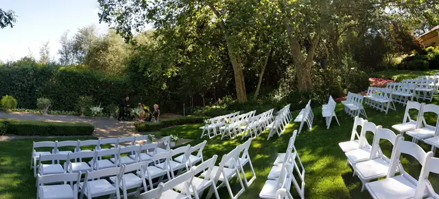 Rows of white folding chairs set across the lawn at The Madrona ceremony garden in Healdsburg