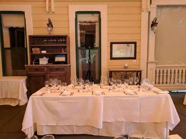 Head table set with glassware on a covered porch at The Madrona, with a speaker on a stand behind it