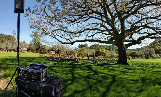 Wayne Noel's ceremony sound rack and speaker set up in the meadow facing rows of chairs under the big tree at Triple S Ranch