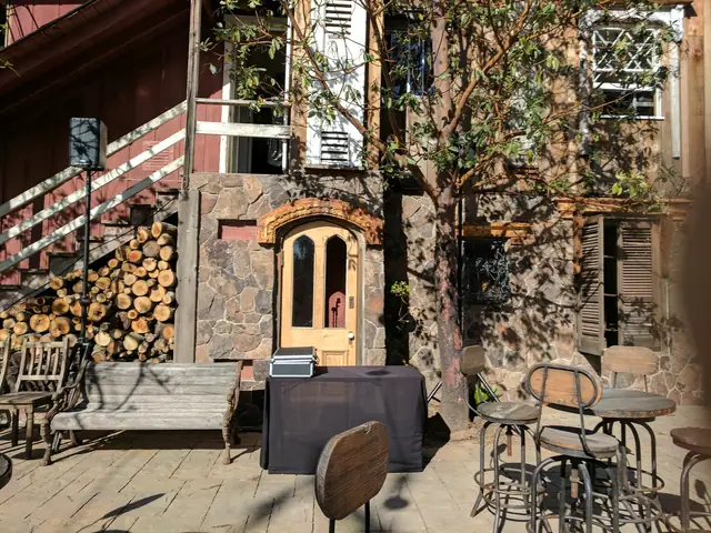 Stone patio at Triple S Ranch with an arched wooden door, stacked firewood and a speaker set up for cocktail hour