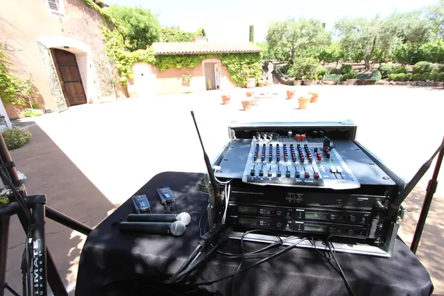 DJ sound rig set up on a draped table in the stone courtyard at Viansa Winery in Sonoma, with the ivy cottage, fountain and olive trees behind