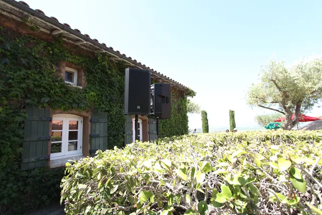 Speakers on stands beside the ivy-covered stone building with green shutters at Viansa Winery