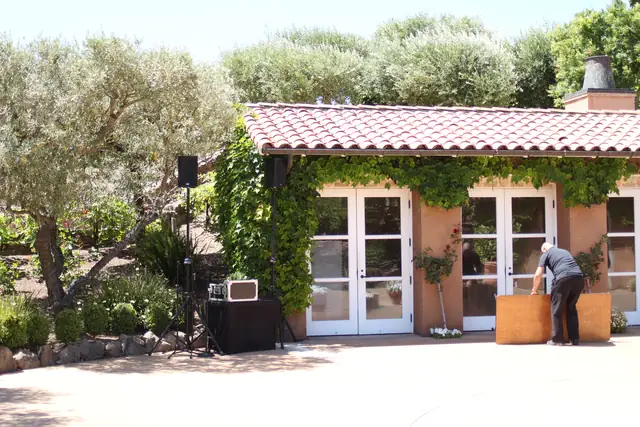 DJ speakers and table set up beside the white French doors of an ivy-covered building at Viansa Winery