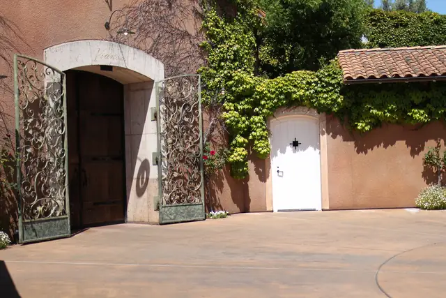 Arched stone entry with open wrought-iron gates and wooden door at Viansa Winery