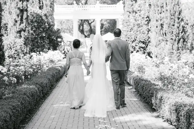 Bride walking the brick garden path toward the white pavilion for the ceremony at Villa Montalvo, in black and white