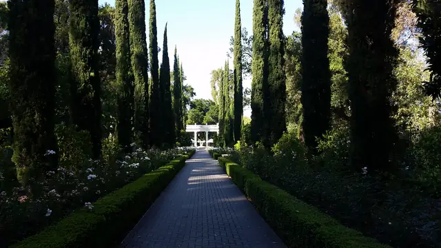 Looking down the cypress-lined brick path toward the white pavilion in the gardens at Villa Montalvo