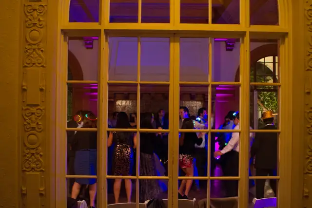 Guests dancing in the uplit ballroom seen through the arched French doors at Villa Montalvo